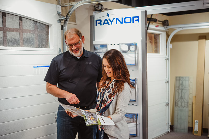 Photo of Female Customer Interacting with Garage Door Specialist and Reviewing Garage Door Pamphlet in Front Range Raynor Showroom in Fort Collins, Colorado